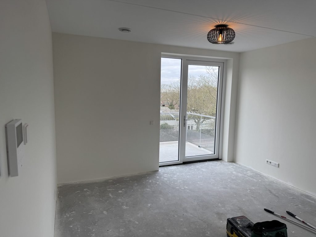 Lege, lichte nieuwbouwkamer met openslaande deuren naar een balkon